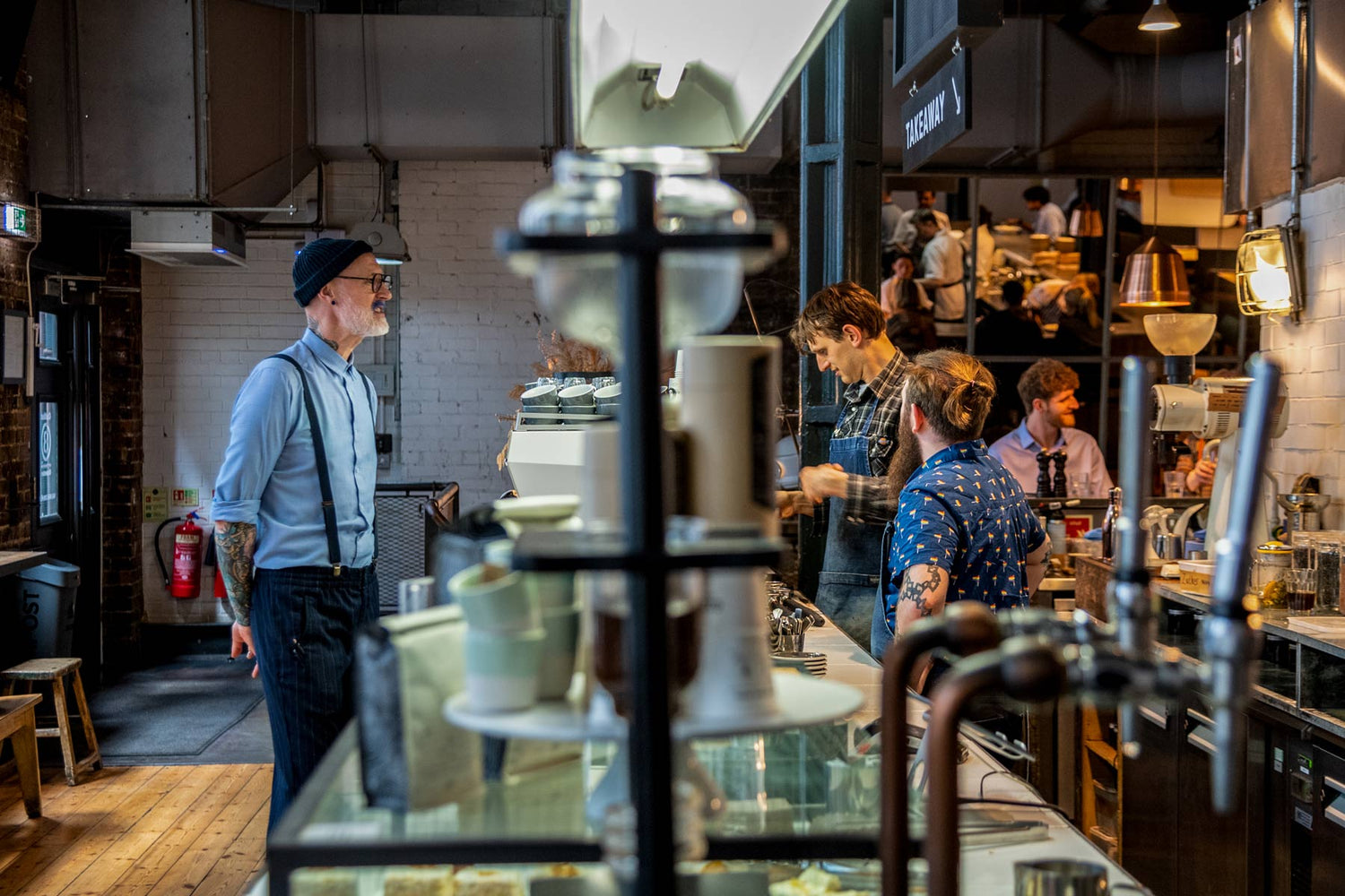 Interior of Ozone Coffee Roasters Shoreditch – busy café scene with baristas, espresso machine, and industrial decor.