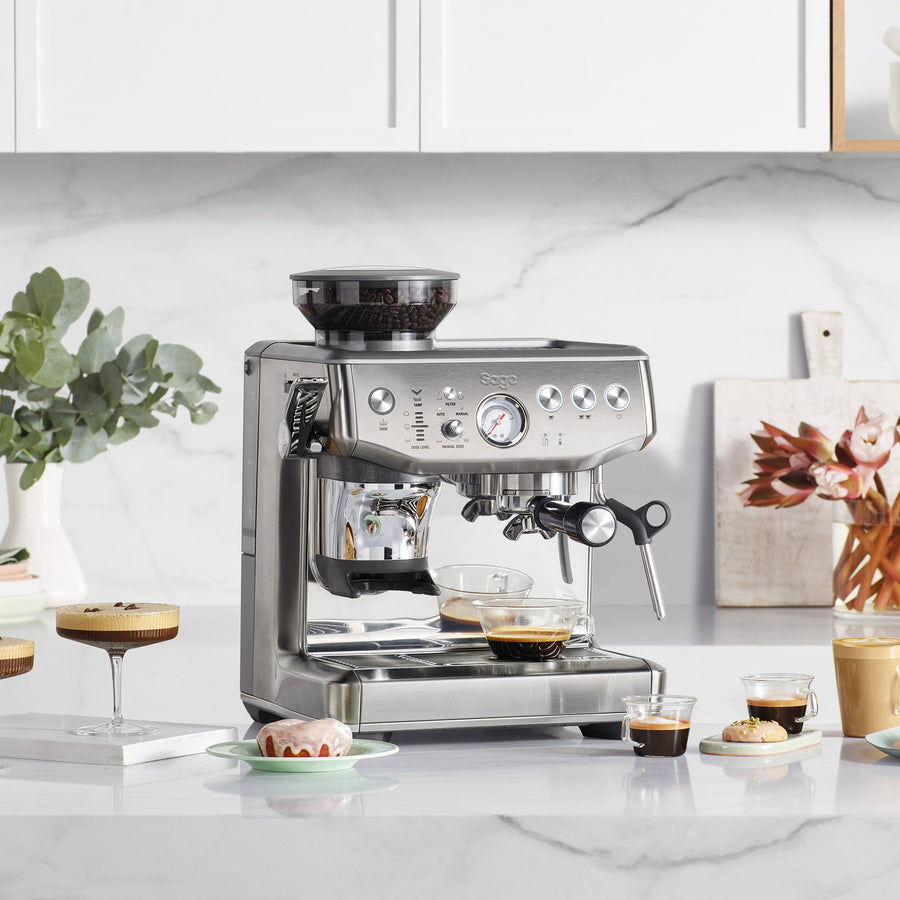 Sage Barista Express™ Impress SES876 Home Espresso Machine on a kitchen counter with coffee and pastries.