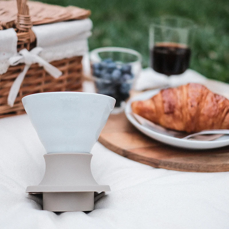 White Hario Switch V60 Ceramic Immersion Dripper - Jasmine White (Size 02) on a table with a croissant and blueberries in the background
