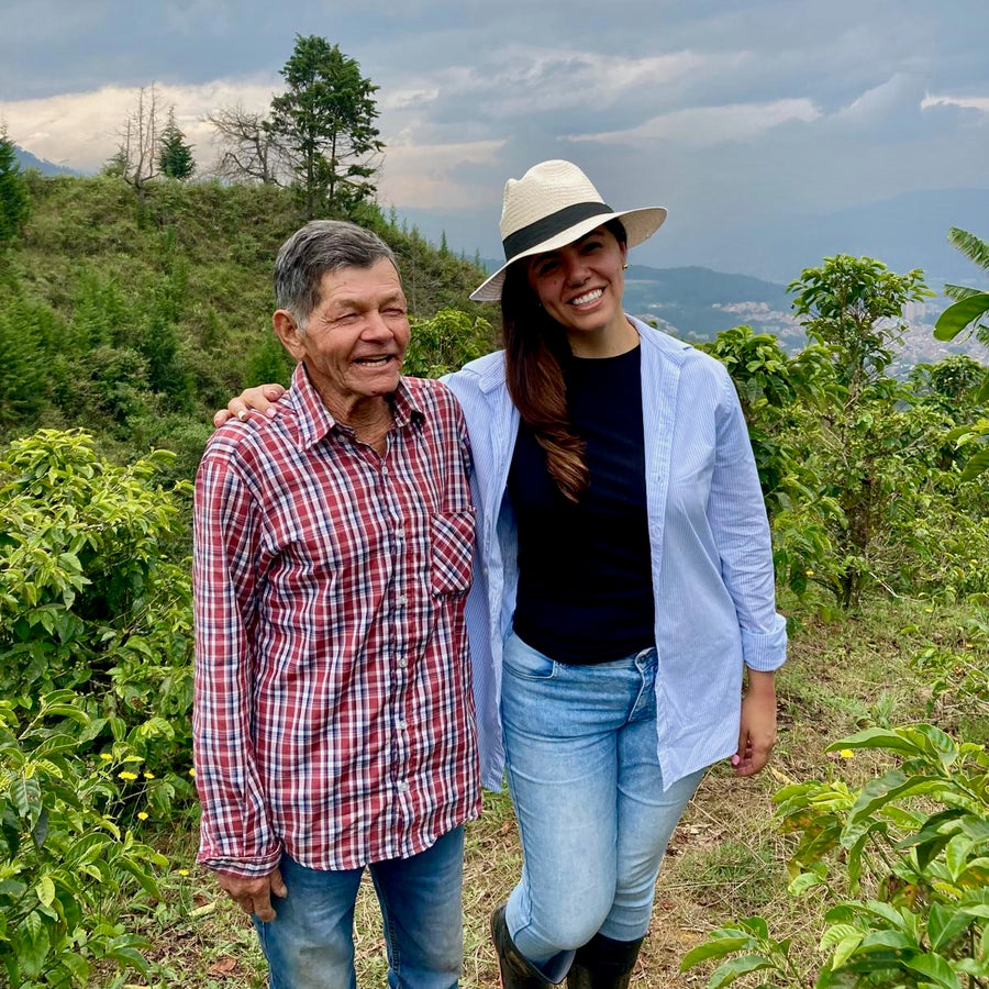 Don Gabriel Cortes and Diana Shanks of Colombian Artisan Coffee stood together at El Tractor in Antioquia, Colombia with the city of Medellín in the background