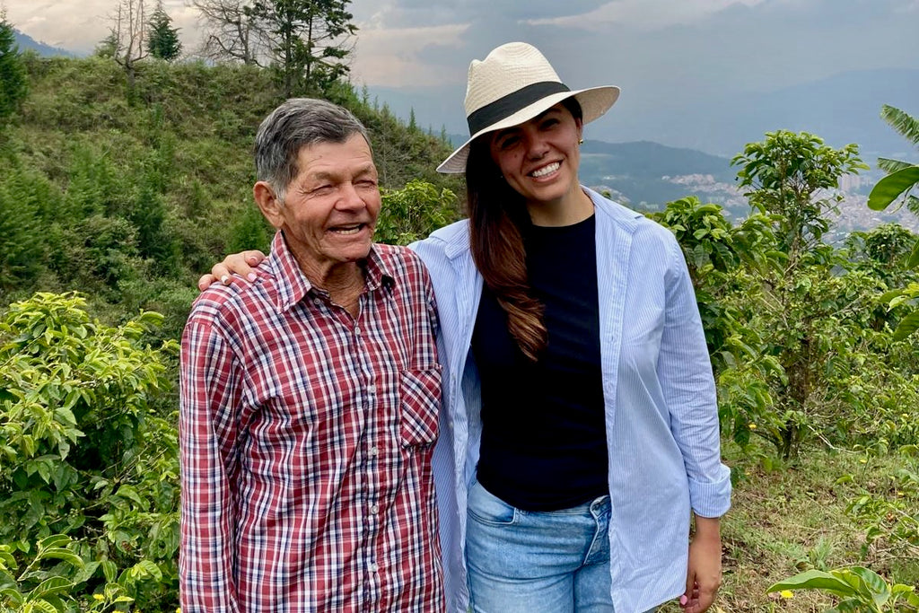 Don Gabriel Cortes and Diana Shanks of Colombian Artisan Coffee stood together at El Tractor in Antioquia, Colombia with the city of Medellín in the background