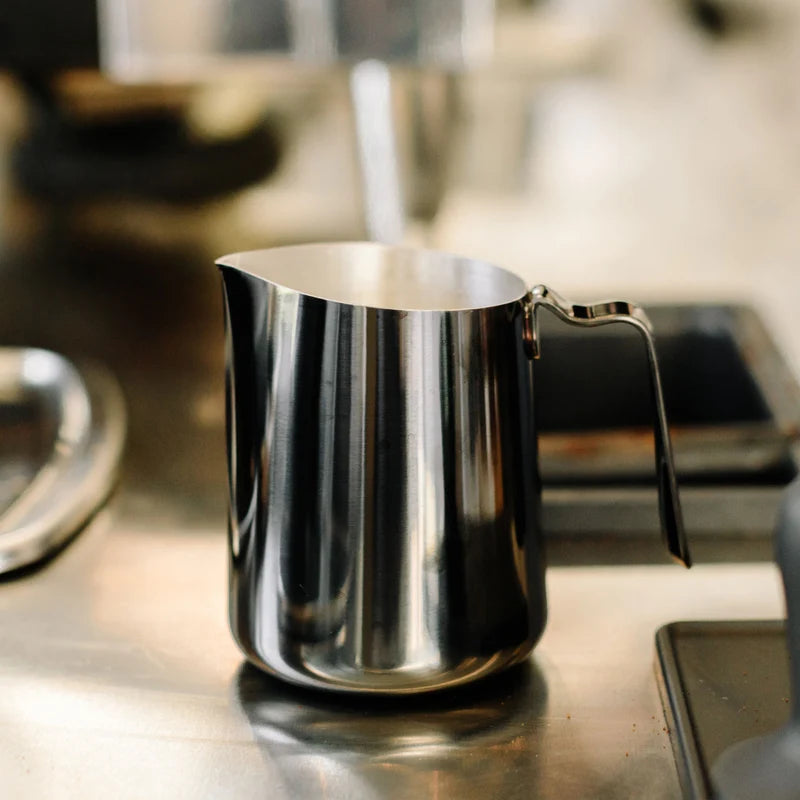Fellow Eddy Steaming Pitcher - Polished Graphite 18oz on a worktop waiting to be used to steam some excellent milk and pour latte art