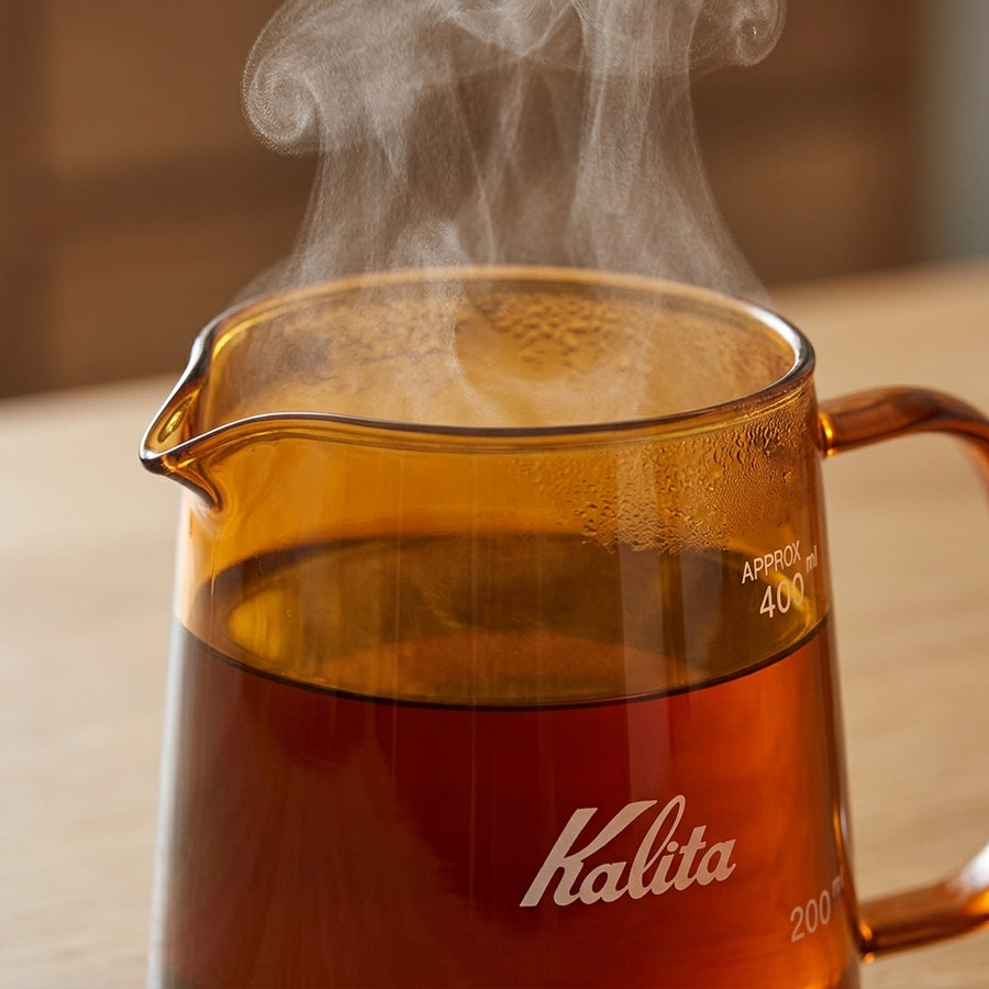 Kalita Jug 400 glass coffee server lifestyle image, with jug filled with hot freshly brewed coffee on a wooden table