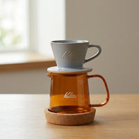 Kalita Jug 400 glass coffee server brewer image including a Kalita MI ceramic 155 dripper on top, on a wooden table. Brewer sold separately and only shown as an example.