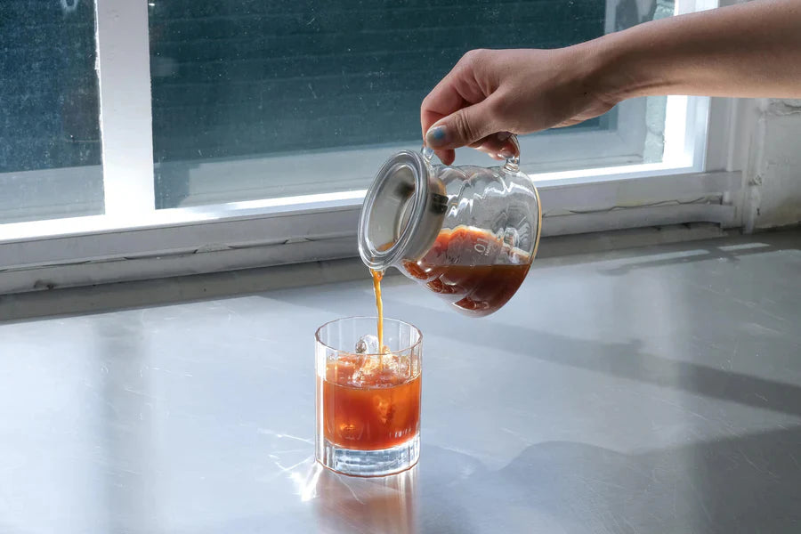 Cold brewed coffee being poured into a glass over ice