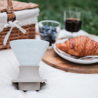 White Hario Switch V60 Ceramic Immersion Dripper - Jasmine White (Size 02) on a table with a croissant and blueberries in the background