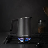 Subminimal FlowTip Milk Jug 450ml, Black with Handle being heated on a gas hob