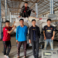 Five coffee producers at a warehouse in Doi Pangkhon, Thailand, standing in front of a large stack of parchment coffee sacks with a digital scale in view.
