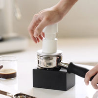 Timemore Impulse Impact Tamper 58.4mm, White, being used to tamp a portafilter on a tamping block