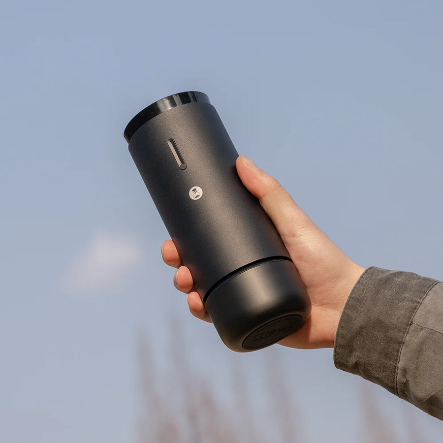 Timemore Whirly 01S Portable Electric Coffee Grinder being held in someone's hand and held up to the sky