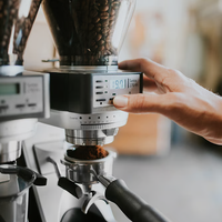 Person adjusting a Baratza Sette 270Wi Coffee Grinder with coffee beans inside, blurred background